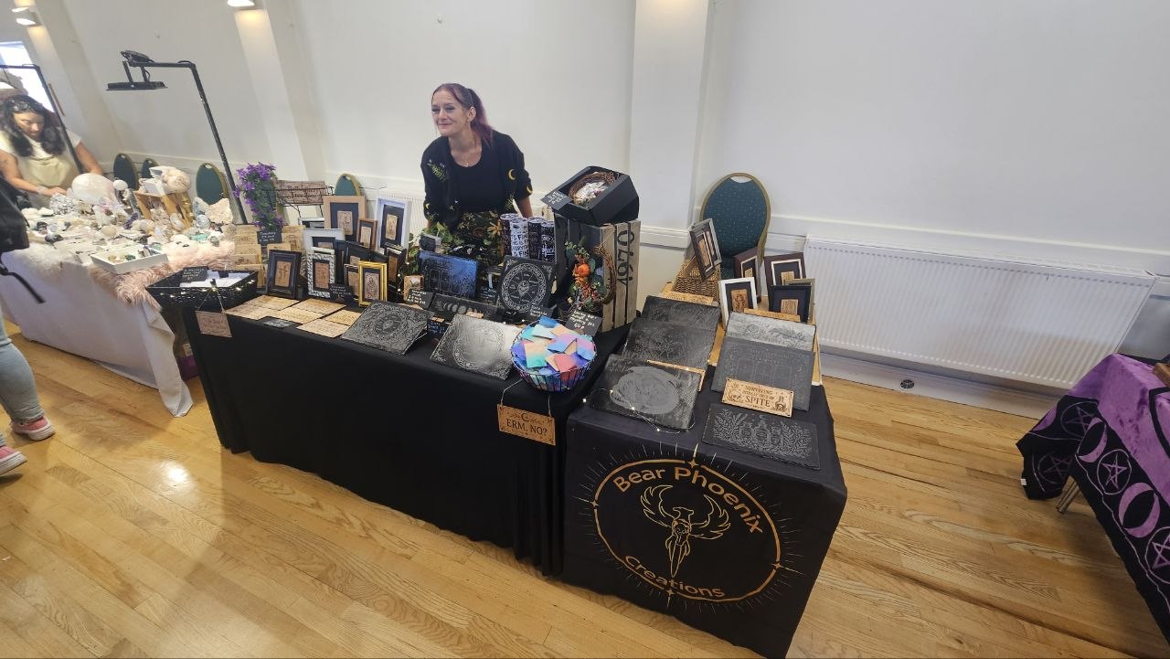 The complete Bear Phoenix Creations stall with engraved wood, slate, framed cards and Amiee behind the display
