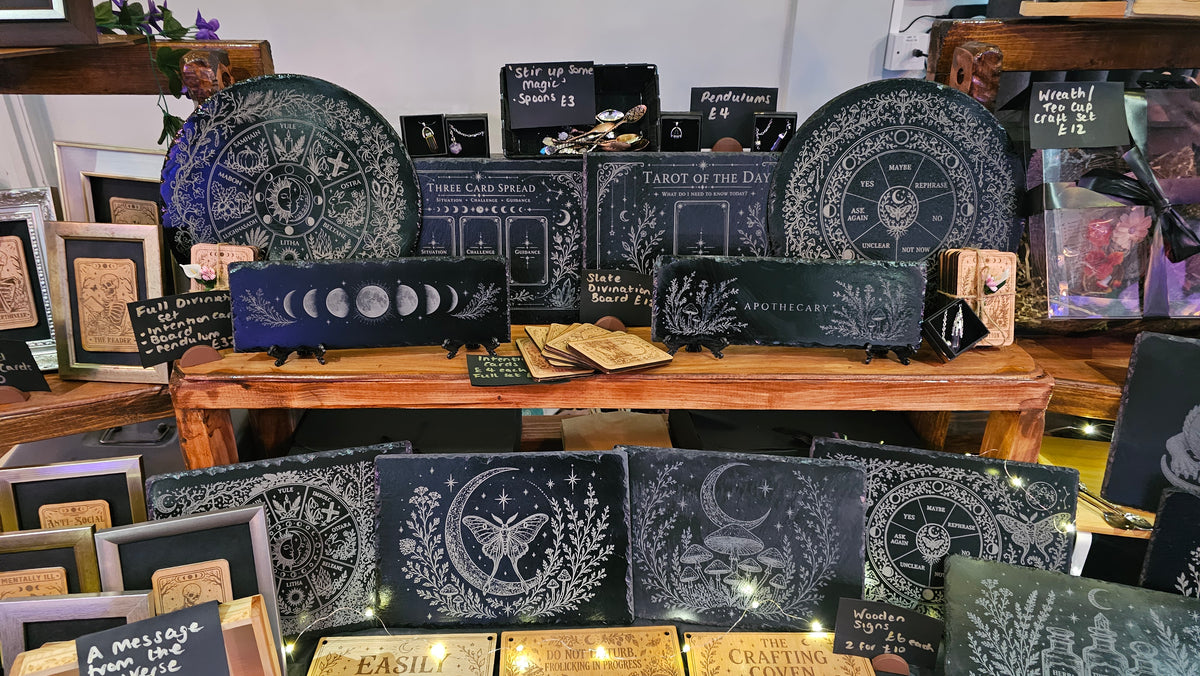 The complete Bear Phoenix Creations stall with engraved wood, slate, framed cards and Amiee behind the display